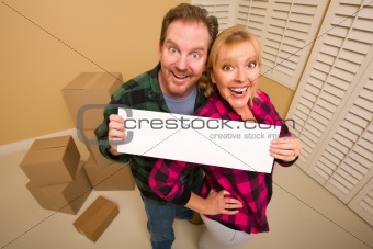 Happy Goofy Couple Holding Blank Sign in Room with Packed Boxes.