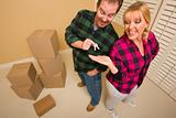 Goofy Excited Man Handing Keys to Smiling Wife in Room with Packed Boxes.