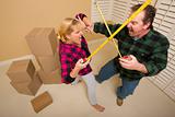 Couple Having a Fun Sword Fight with Their Tape Measures Surrounded by Packed Moving Boxes.