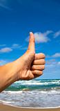 Thumb up hand sign with beach background