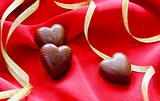 Chocolate hearts and gold ribbon on a red background.