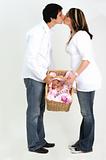 couple holding new baby in basket while kissing