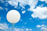 Golf ball and tee in front of a cloudy sky