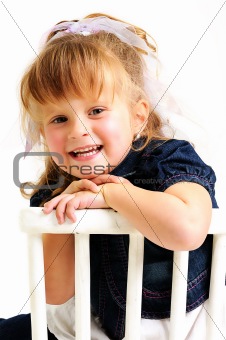 Pretty blond girl in blue dress sitting on white chair