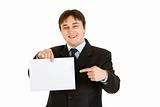 Smiling modern businessman pointing finger at empty white  paper 
