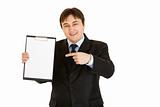Smiling modern businessman pointing finger at blank clipboard
