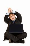 Smiling  businessman sitting on floor with laptops and showing  partnership gesture
