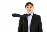 Surprised young businessman with blowing necktie
