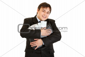 Successful businessman hugging briefcase with money in hands
