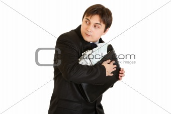 Wary businessman hugging briefcase with money in hands

