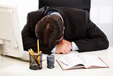 Tired businessman sleeping at  desk in  office 
