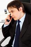 Attentive  young businessman talking on  telephone in office
