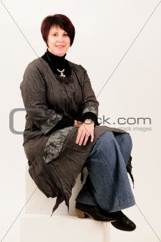 Beautiful attractive mature woman sitting in blue jeans and coat