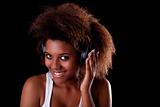 Beautiful black woman happy listening music in headphones, isolated on black background. Studio shot.