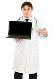 Serious medical doctor pointing finger on laptops blank screen
