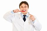 Smiling dentist pointing finger on toothbrush. Concept - healthy teeth