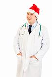 Smiling medical doctor in hat of Santa Claus  looking up at copy space
