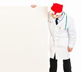 Medical doctor in Santa hat looking at blank billboard
