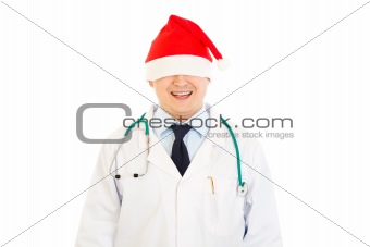 Smiling medical doctor in Christmas hat stretched over his eyes
