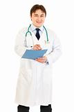 Smiling medical doctor writing report in medical chart of patient
