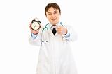 Smiling  medical doctor pointing finger on  alarm clock
