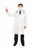 Medical doctor wearing mask and pointing  finger in corner
