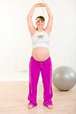 Smiling beautiful pregnant woman doing exercise at home

