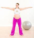 Smiling beautiful pregnant female doing exercise at home
