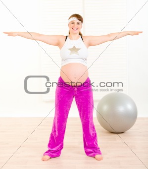 Smiling beautiful pregnant female doing exercise at home
