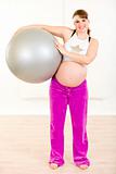 Smiling beautiful pregnant woman holding fitness ball in hands
