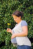 Pregnant woman holding her belly and yellow flower