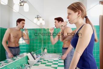 husband and wife brushing teeth in bathroom