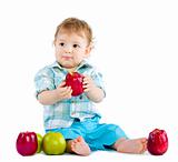 Beautiful baby boy eats red apple.