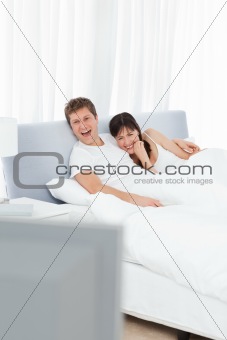 Couple watching tv in their bed