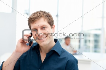 Happy businessman phoning in his office