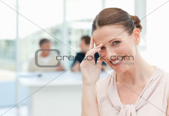 Smiling businesswoman looking at the camera while her coworkers 