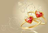 Two gold rings with gems on beige background