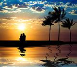 The silhouette of couple watching sunset on the beach