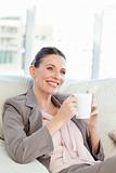 Happy businesswoman drinking a cup of coffee in her sofa