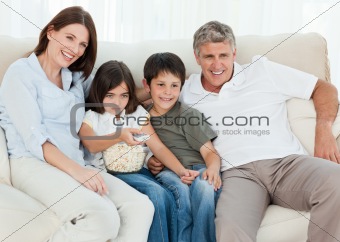 Family watching tv while they are eating popcorn