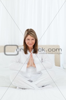 Senior practicing yoga on her bed