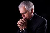 Portrait of a handsome mature businessman, thinking, praying,  on black background, studio shot