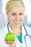 Smiling Woman Doctor in Hospital Holding Green Apple