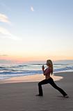 Beautiful Woman Practicing Yoga on Beach At Sunrise or Sunset