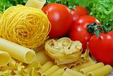 Different varieties of pasta, ripe tomatoes and greens.