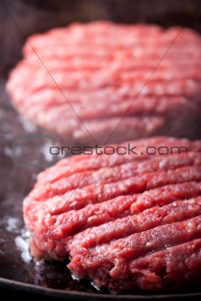 two beef patties in an iron pan