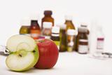 green and red apples in front of many pills and pill