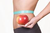 woman holding an red apple while measuring her waist
