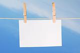 blank paper and clothes peg on blue sky