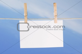 blank paper and clothes peg on blue sky